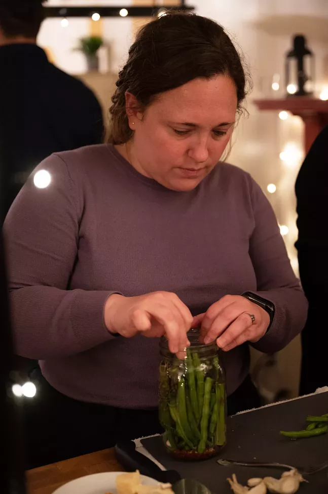 Adding green beans to a jar during fermentation workshop